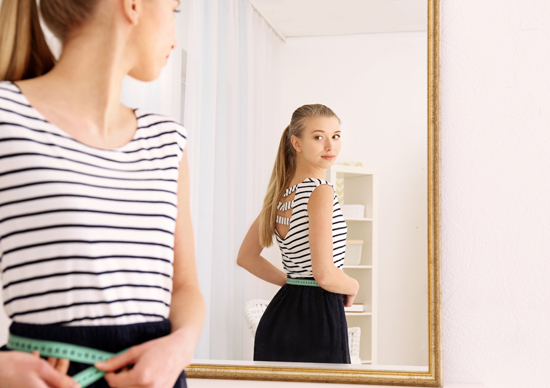 女性が鏡の前で身だしなみをチェックしている写真